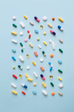 Mavi arka planda renkli hapların ve kapsüllerin yaratıcı tasarımı. Asgari tıbbi konsept. Eczacılık, Covid-19 veya Coronavirus. Düz yatış, üst görünüm