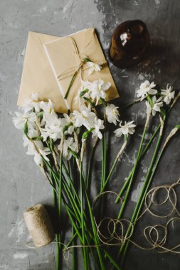 Bir buket nergis çiçeği, desenli gri arkaplanda bir tebrik kartı. Düz konum, üst görünüm, kopyalama alanı. Çiçek kompozisyonu. Bahar, Paskalya, yaz konsepti.