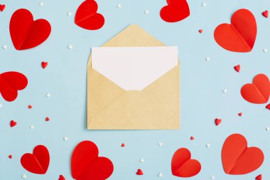 Sevgililer Günü geçmişi 14 Şubat. Boş tebrik kartı sahnesi, konfeti, pastel mavi arka planda kırmızı kalpler. Sevgililer Günü konsepti. Düz konum, üst görünüm, kopyalama alanı