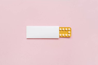 Hormonal oral doğum kontrol hapları bir aylık resepsiyonda pastel pembe arka planda yatıyor. Düz konum, üst görünüm, kopyalama alanı.