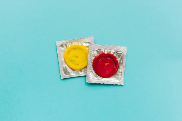 Composição colorida com preservativos amarelos e vermelhos sobre fundo azul brilhante. Sexo seguro e conceito contraceptivo. Flat lay, vista superior, espaço de cópia. — Fotografia de Stock