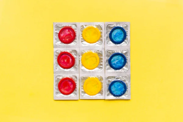Komposition mit bunten Kondomen auf gelbem Hintergrund. Sicherer Sex und Verhütungsmittel. Flache Lage, Draufsicht, Kopierraum. — Stockfoto