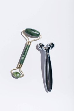 Yeşim yüz silindiri ve beyaz arka planda gölgeli yüz masajı. Düz yatış, üst görünüm