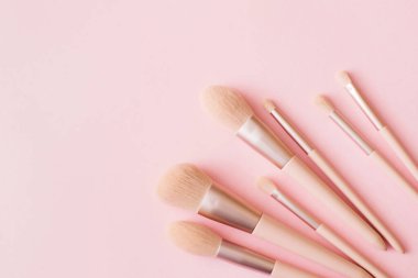 Pembe arka planda makyaj fırçaları. Pastel renkte kadın güzellik aksesuarı. Düz konum, üst görünüm, kopyalama alanı