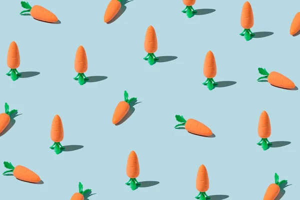 Easter pattern made with carrots on blue background. Creative minimal holiday concept. Flat lay, top view.