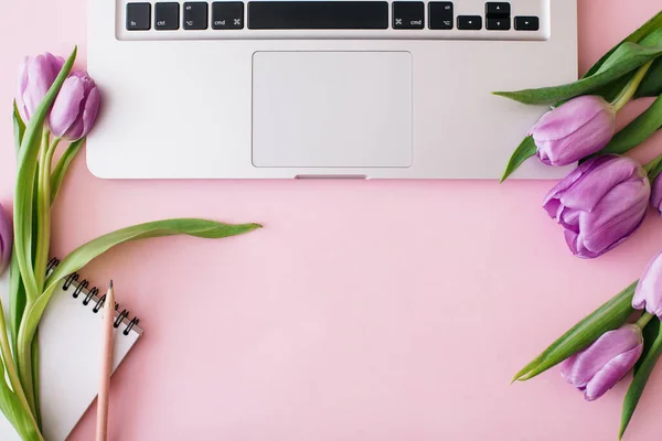 Espaço de trabalho com laptop, flores de tulipa, xícara de café em fundo rosa. Escritório de casa. Flat lay, vista superior, espaço de cópia para texto. Conceito Primavera. — Fotografia de Stock