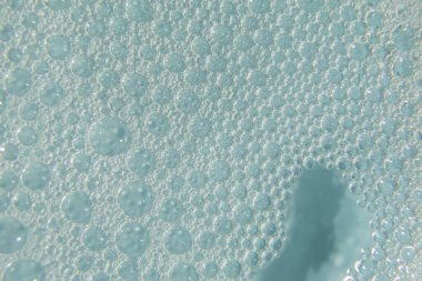 Köpüklü kozmetik doku ve mavi arka planda kabarcıklar. Temizleyici, şampuan, yıkama - sıvı sabun, duş jeli, hyaluronik asit, serum. Kopyalama alanı olan kozmetik pankartı