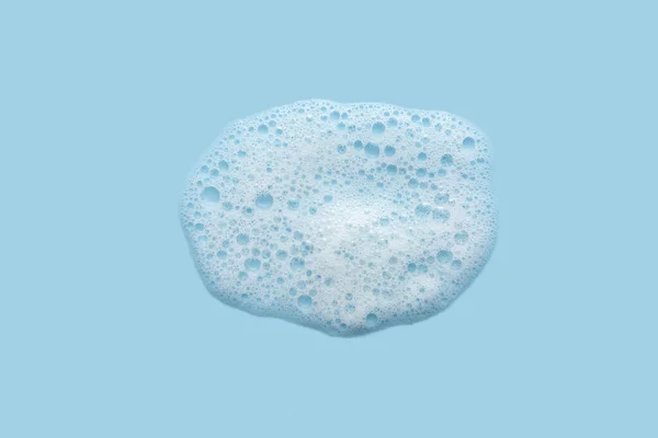 White cosmetics foam texture on blue background. Cleanser, shampoo bubbles, wash - liquid soap, shower gel, shampoo. Texture of white foam on rose background. Cosmetics banner with copy space — Stock Photo, Image