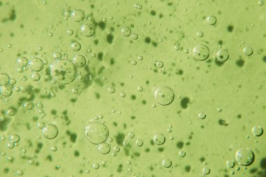 Pastel yeşil arka planda köpüklü kozmetik doku. Temizleyici, şampuan, yıkama - sıvı sabun, duş jeli, hyaluronik asit, serum. Kozmetik afişi.