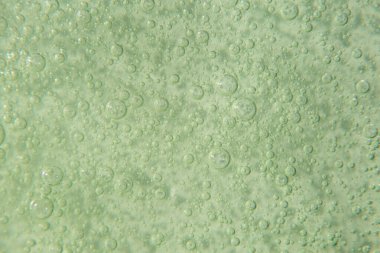 Pastel yeşil arka planda köpüklü kozmetik doku. Temizleyici, şampuan, yıkama - sıvı sabun, duş jeli, hyaluronik asit, serum. Kozmetik afişi