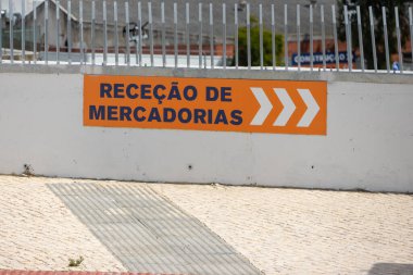 Orange sign with white arrows pointing to goods receiving area at obramat building materials store