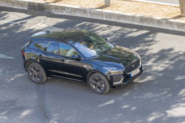 Siyah jaguar ve tempo küçük jip ağaç gölgeli şehir yolunda ilerliyor.