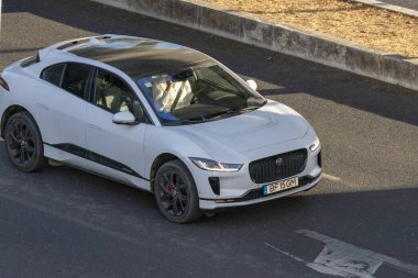 Beyaz jaguar. Elektrikli araba gündüz yolda ilerliyor.