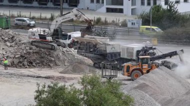 Kazıcı inşaat alanındaki enkazı öğütücüye yüklüyor