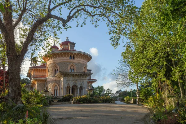 Melez saray yemyeşil bir bahçede duruyor ve mavi bir gökyüzünün altına park ediyor.