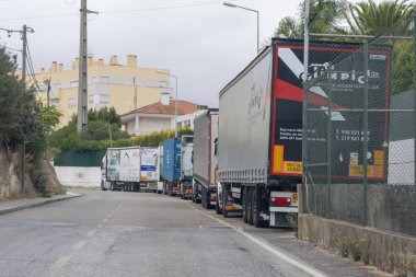 Yarı karavan kamyonları bir caddede uzun bir kuyrukta, nakliye lojistiği için bekliyorlar.