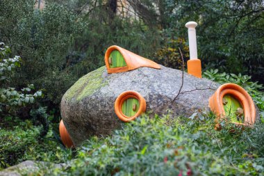 Turuncu aksanlı ve botanik bahçesine yerleştirilmiş yeşil kapılı neşeli peri evi.