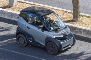 Elektrikli mikro araba kullanan adam sürdürülebilir şehir ulaşımını sembolize ediyor.