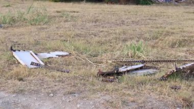 Rusty metal debris lies abandoned in a dry field, highlighting environmental pollution and irresponsible waste disposal