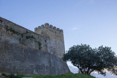 Palmela Kalesi 'nin antik taş duvarları ve bir ağacın tepesinde yükselen çentikli kule