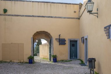 Palmela Kalesi 'nin kaldırım taşı avlusu kemerli taş bir giriş ve eski duvarları gösteriyor.