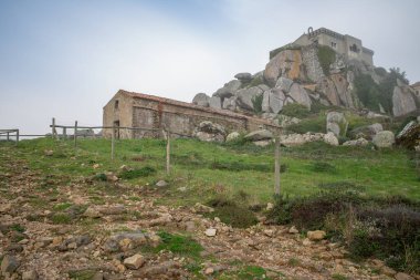 Peninha tapınak kompleksi kayalık bir tepede, sisli gökyüzünün altında bir şapel ve saray var.