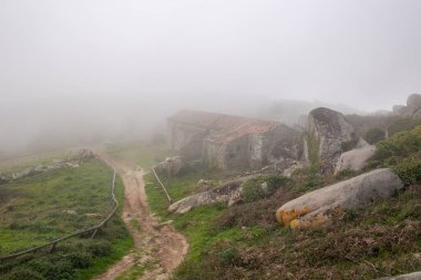 Peninha tapınağı ve saray harabeleri yoğun sisle örtülmüş ve kayalık manzarayla çevrili.