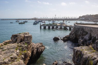 Cascais 'deki Ribeira sahil iskelesinde balıkçı tekneleri ve kayalık kıyı şeridi yer alıyor.