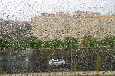 Camdan pencereyi kaplayan yağmur damlaları şehrin caddesini ve Lisbon 'daki binaları bulanıklaştırıyor.