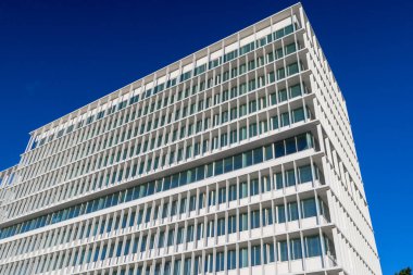 Tekrarlayan beyaz cephe deseni ve mavi gökyüzü olan modern mimari