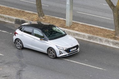 Hyundai i20 hatchback ağaçlar ve kaldırımlarla asfalt bir yolda ilerliyor