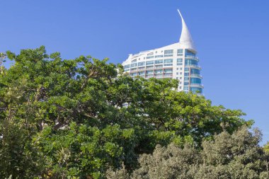 Mavi gökyüzünün altında yemyeşil ağaçların üzerinde yükselen eşsiz mimarisi olan modern yerleşim yeri.