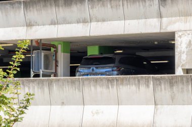 Endüstriyel elementlerin olduğu beton bir otoparka park edilmiş modern bir araba.