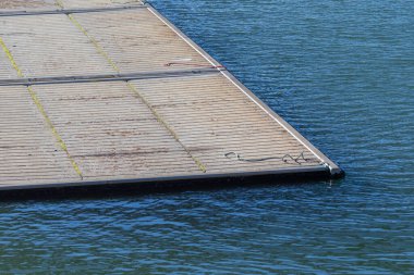 Dalgalanan mavi suyun yanında desenli yüzeyi olan yüzen tekne iskelesi.