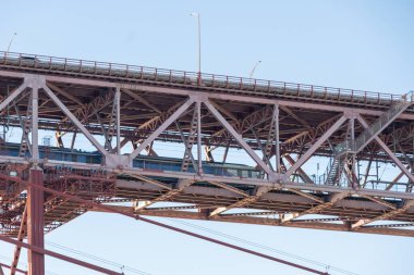 Tren mavi gökyüzü ile 25 Nisan köprüsünün alt güvertesinde ilerliyor.