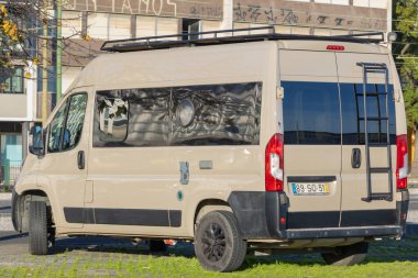 Bir şehir binasının yanındaki yeşil çimlerin üzerine park edilmiş dönüştürülmüş karavan.