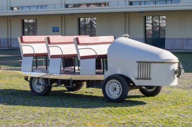 Asfaltlı bir yüzeyde yolcu koltuğu olan eski tip elektrikli servis otobüsü.