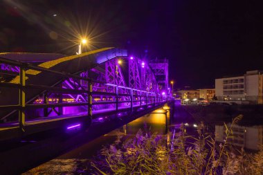 Alcacer Sal Metal Truss Köprüsü 'nün mor noel ışıklarıyla parlaması gece Sado Nehri' ne yansıyor.