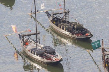 İki geleneksel haham teknesi Douro nehrinde şarap fıçıları taşıyor.