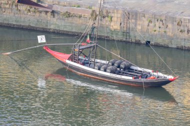 Rabelo teknesi Porto City yakınlarındaki Douro nehrinde şarap fıçıları taşıyor.