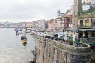 Ribeira bölgesinde renkli binalar, nehir kenarındaki gezinti güvertesi ve Douro Nehri 'ndeki geleneksel tekneler sergileniyor.