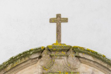 Taş haç, dini bir binanın tepesinde yaş ve liken gösteriyor.