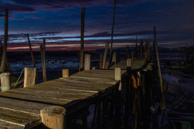 Eski ahşap iskele, sabahın erken saatlerinde çamurlu düzlüklerin üzerinde ayakta duruyor.