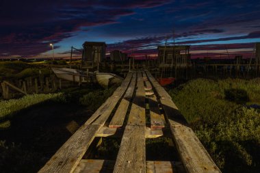 Eski ahşap balıkçı iskelesi ve karrasqueira 'da tahta kulübeler, alacakaranlıkta Portekiz.