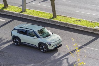 Gündüz vakti asfalt yolda giden Kia ev3 elektrikli araba, modern tasarımı gösteriyor