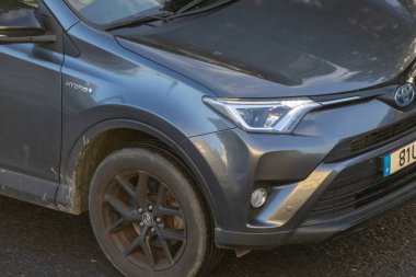 Toyota rav4 hibrit arazi aracı bir caddeye park etmiş, ön bölümünü gösteriyor.