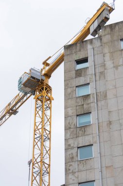 Yüksek katlı inşaat sahasında vinç ağır ekipman kaldırıyor.