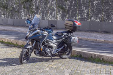 Gri Honda nc750x tur motosikleti valizleri açık şehir ortamında park edilmiş.