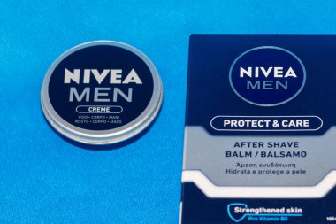 Nivealı erkekler krem sürerler ve mavi arka planda cilt bakımı için tıraş losyonu sürerler.