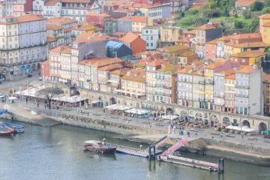 Porto, Portekiz 'deki Douro Nehri' ni çevreleyen renkli tarihi binalar rıhtım boyunca yürüyen insanlarla dolu.